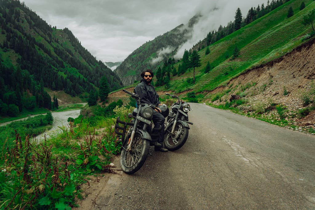 A men on royal enfield bike with beautiful mountain view behind in gurez valley
