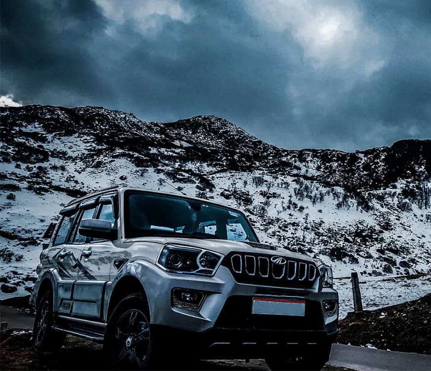 cab-rentals Mahindra scorpio with snow-capped mountain behind it