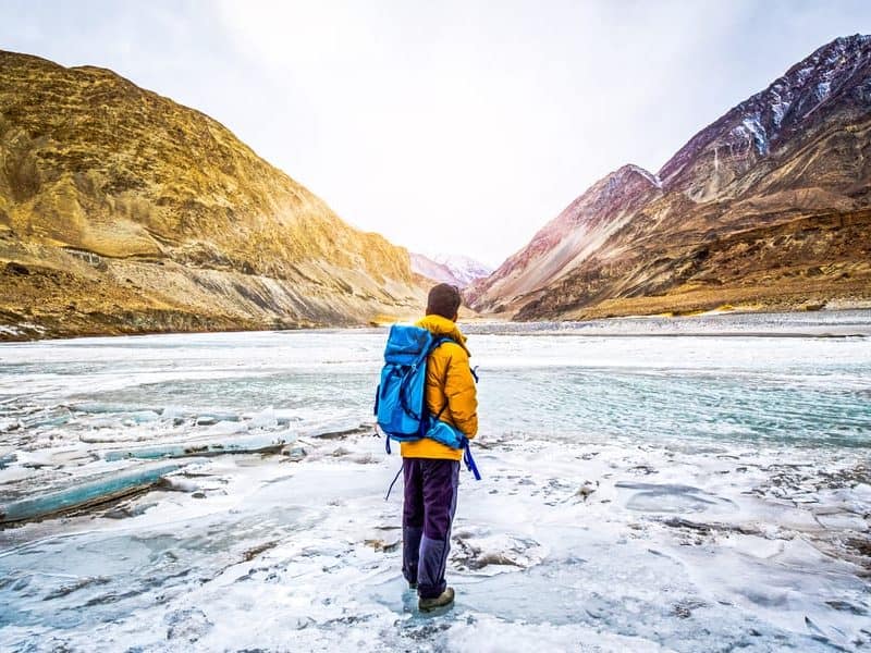 boy standing infront of river and mountains for kashmir tour itineraries from kashmir travelogue.